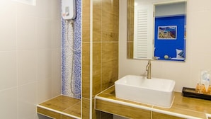 Een badkamer met een wit wastafelmeubel, een spiegel en een douche met blauwe en bruine tegels.