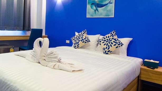 Een hotelkamer met een bed, een bureau, een stoel en een walvis op het schilderij aan de muur.