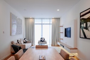 A modern living room with a large window, a dining table, and a sofa. - The Riyaz Lavanya (Langkawi)