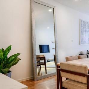 A modern dining area with a large mirror, a potted plant, and a television on the wall. - The Riyaz Lavanya (Langkawi)
