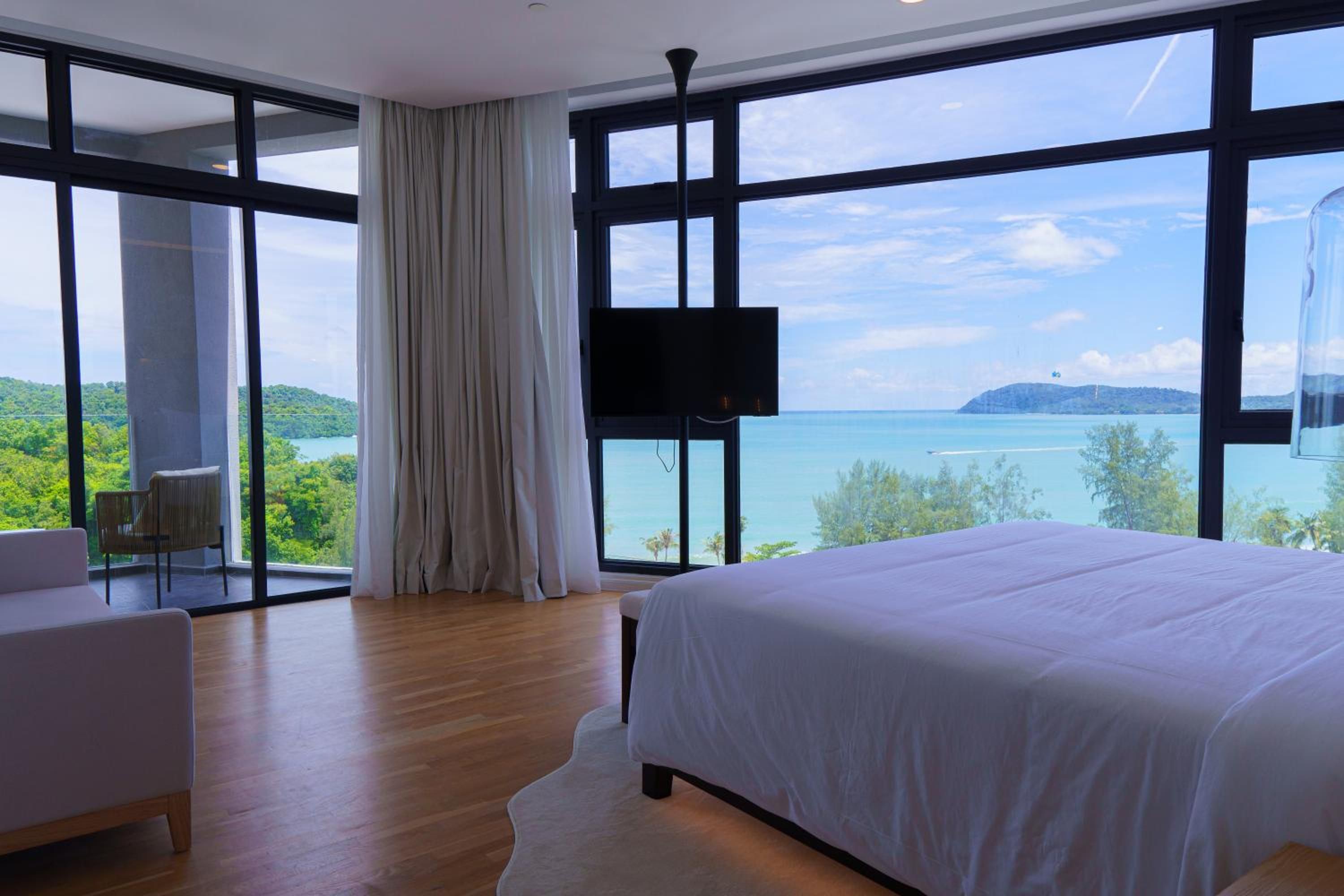 Une chambre avec un grand lit, une télévision et une vue sur la mer.