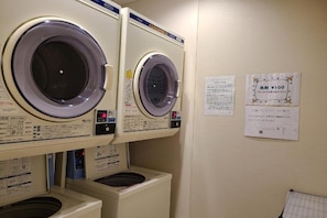 A laundry facility with multiple washing machines and instructional signs on the wall. - Ai Hotel Hashimoto (Sagamihara)