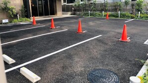 A hotel entrance with a modern design, marked parking spaces, and a gated entrance. - Ai Hotel Hashimoto (Sagamihara)