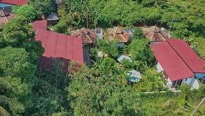 Un groupe de maisons aux toits rouges, entourées d’une végétation luxuriante.