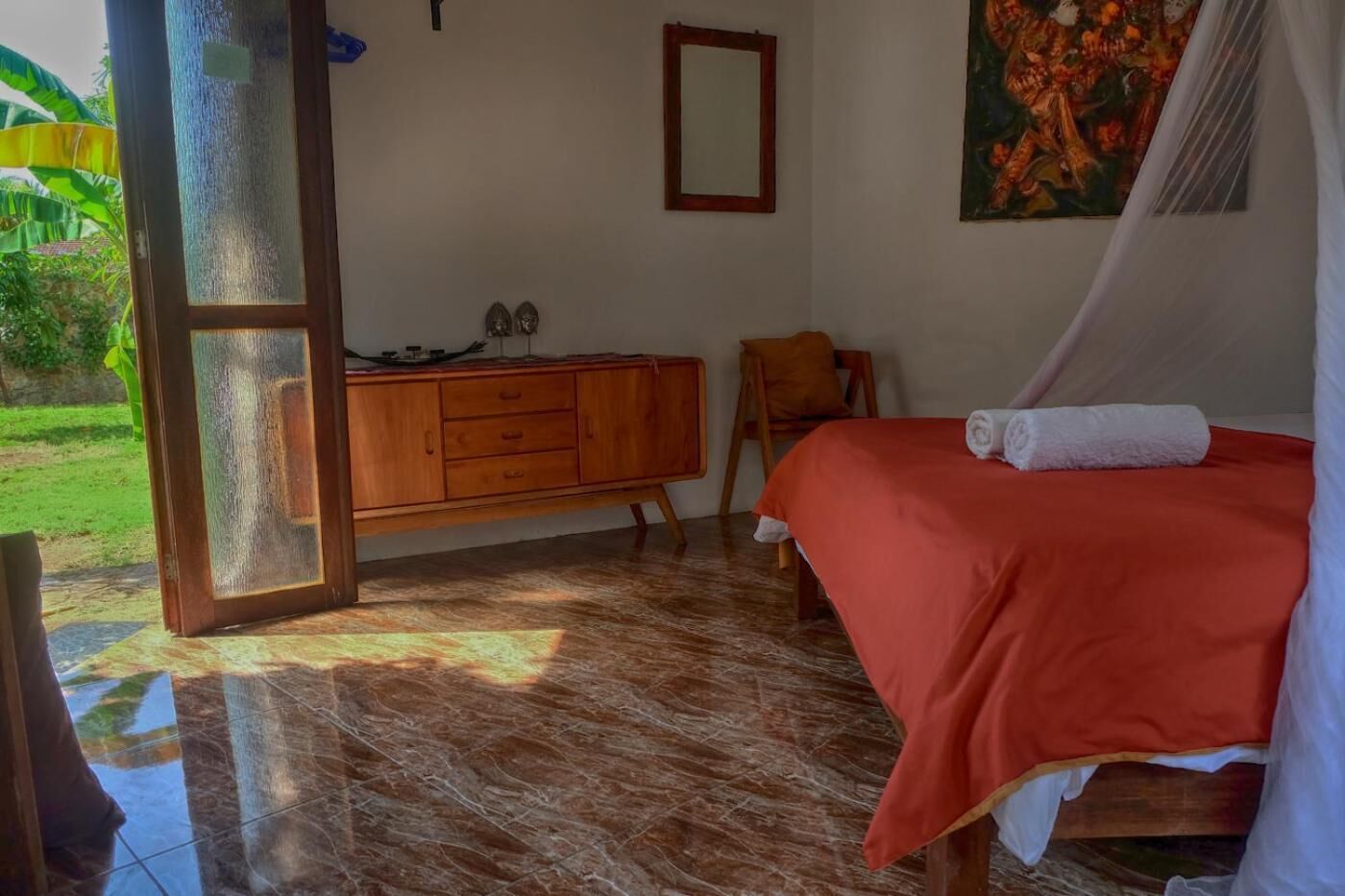 Un dormitorio con una cama, un aparador de madera, un espejo y un cuadro en la pared.