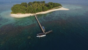 Vue aérienne d’une île tropicale, avec une voie navigable dégagée menant à un quai.