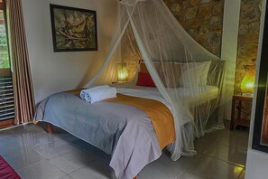 Uma cama com dossel, um quadro na parede e uma parede de pedra.
