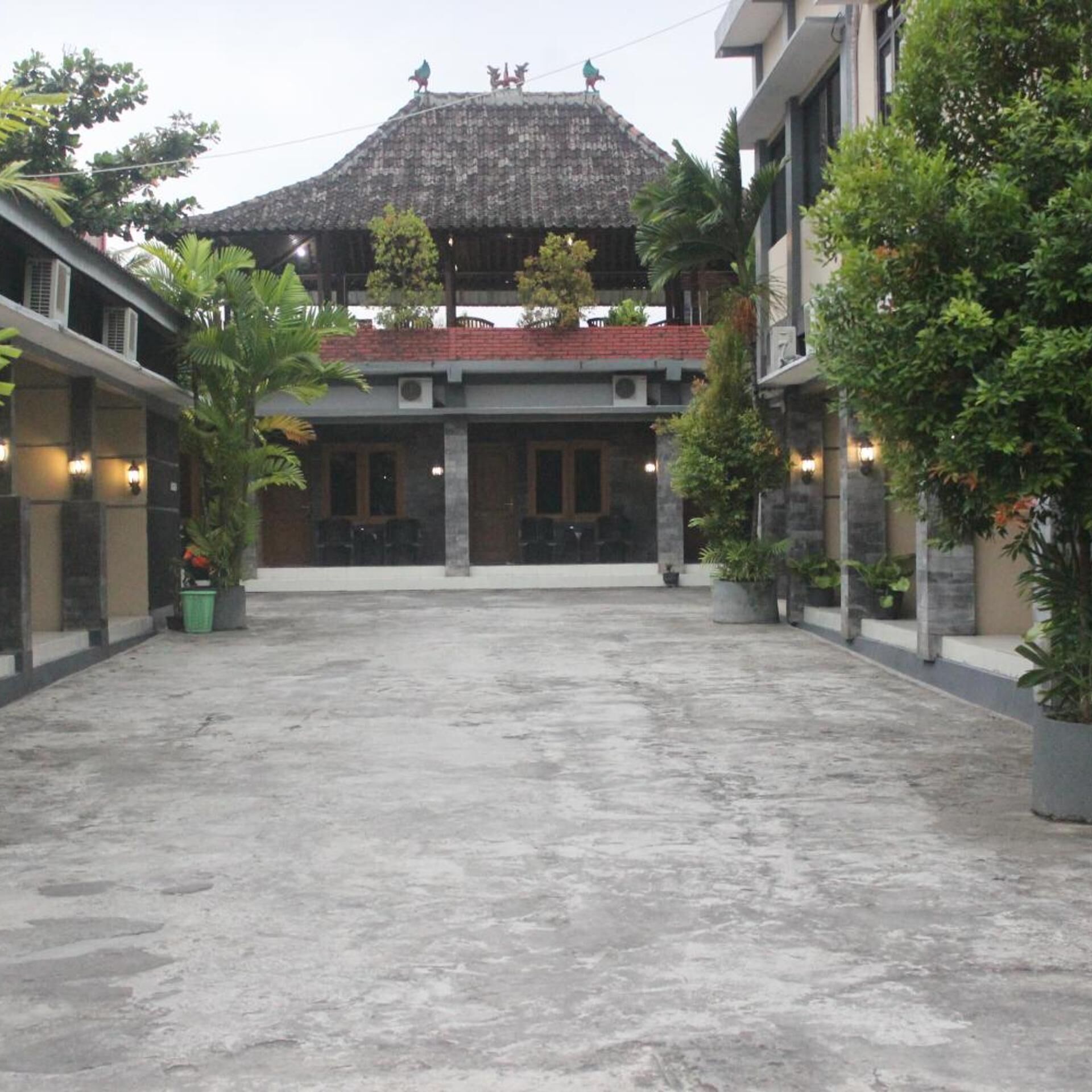 A courtyard with a central building featuring a tiled roof and a balcony with decorative elements.