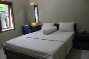 A bedroom with a bed, a dresser, a mirror, and a window. - Cyka Raya Hotel (Wonosari)