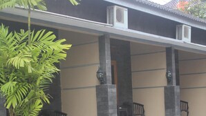 Un espacio al aire libre cubierto con una planta en maceta, dos bancos y suelo de baldosas.