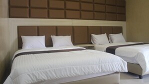 Una habitación de hotel con dos camas, cabecero acolchado y ropa de cama blanca.