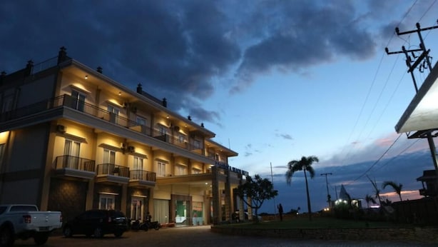 A multi-story hotel with balconies, a well-lit entrance, and a view of the sea. - Padadita Beach Hotel (Waingapu)