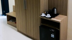 A wooden wardrobe with a built-in mini-fridge and a shelf with cups and a kettle. - Padadita Beach Hotel (Waingapu)