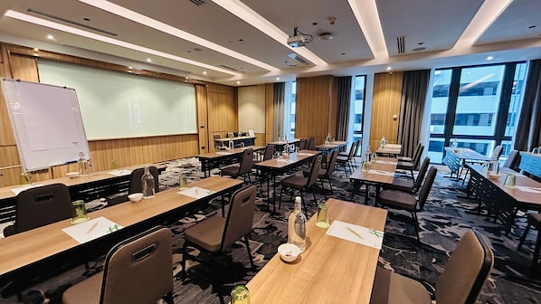 A conference room with tables, chairs, a whiteboard, and a projector screen. - Holiday Inn Sepang Airport (Sepang)