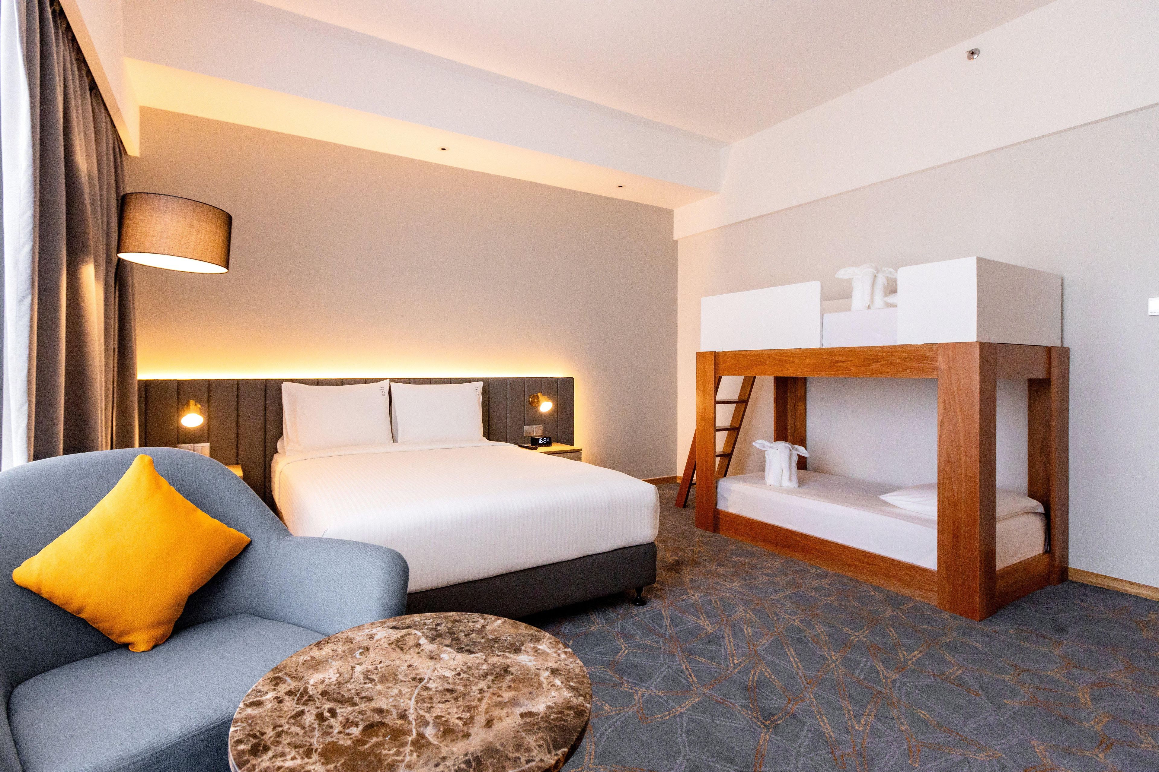 Ein Hotelzimmer mit einem Bett, einer Schlafcouch, einem kleinen runden Tisch und einem Etagenbett.