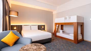 Ein Hotelzimmer mit einem Bett, einer Schlafcouch, einem kleinen runden Tisch und einem Etagenbett.