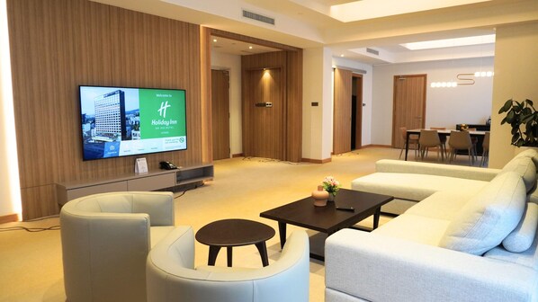 Un hall d’hôtel moderne doté d’un téléviseur à écran plat, d’un canapé, d’une table basse et d’un coin repas.