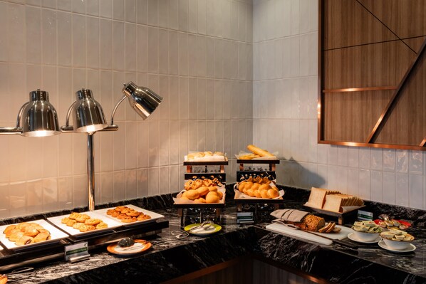 A buffet with various food items, a marble countertop, and a wall-mounted lamp. - Holiday Inn Sepang Airport (Sepang)