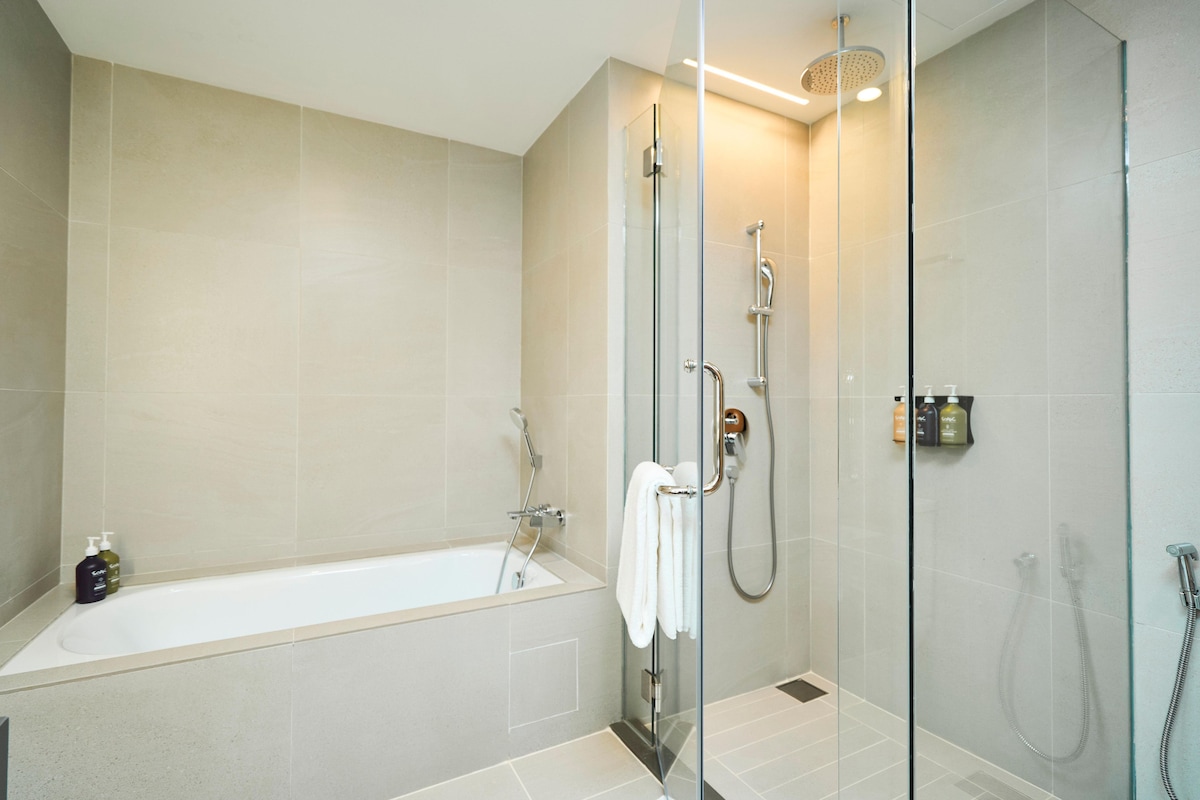 A modern bathroom with a glass-enclosed shower, a bathtub, and a glass door.