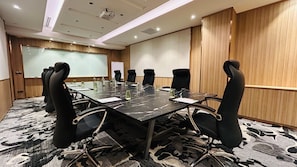 A conference room with a long table, black chairs, a projector screen, and a whiteboard. - Holiday Inn Sepang Airport (Sepang)