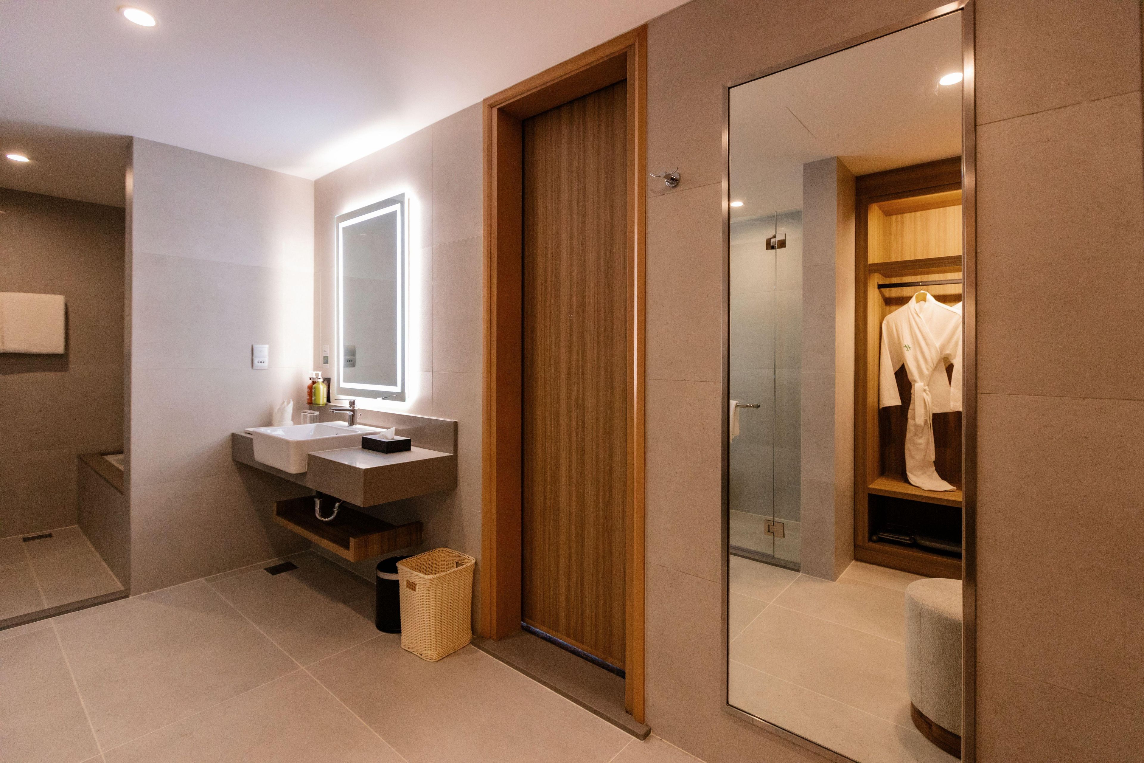 A modern bathroom with a wooden vanity, a mirror, and a glass shower enclosure.