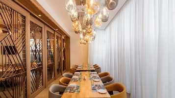 A dining area with a long table, chairs, and a modern chandelier.