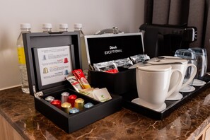 A coffee station with a coffee maker, cups, and a box containing coffee capsules and a bottle of water. - Holiday Inn Sepang Airport (Sepang)