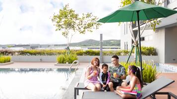 A family of four by a pool with a view of a body of water and hills in the background.