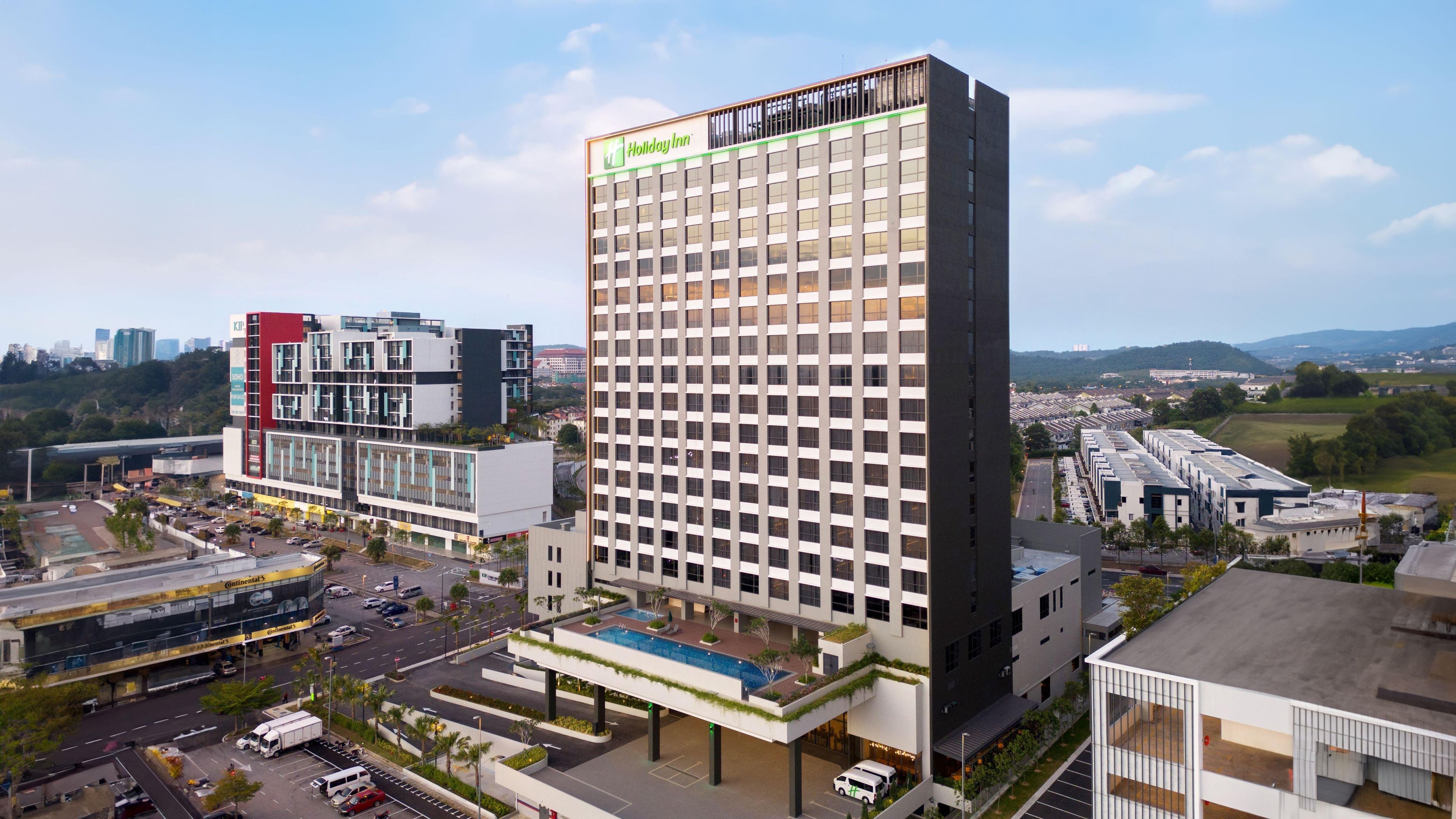 A Holiday Inn hotel with a modern design, featuring a rooftop pool and a view of the surrounding urban area.