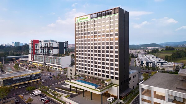 A Holiday Inn hotel with a modern design, featuring a rooftop pool and a view of the surrounding urban area. - Holiday Inn Sepang Airport (Sepang)