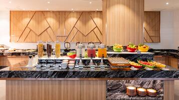 A buffet with various food items and beverages, a marble countertop, and wooden cabinetry.