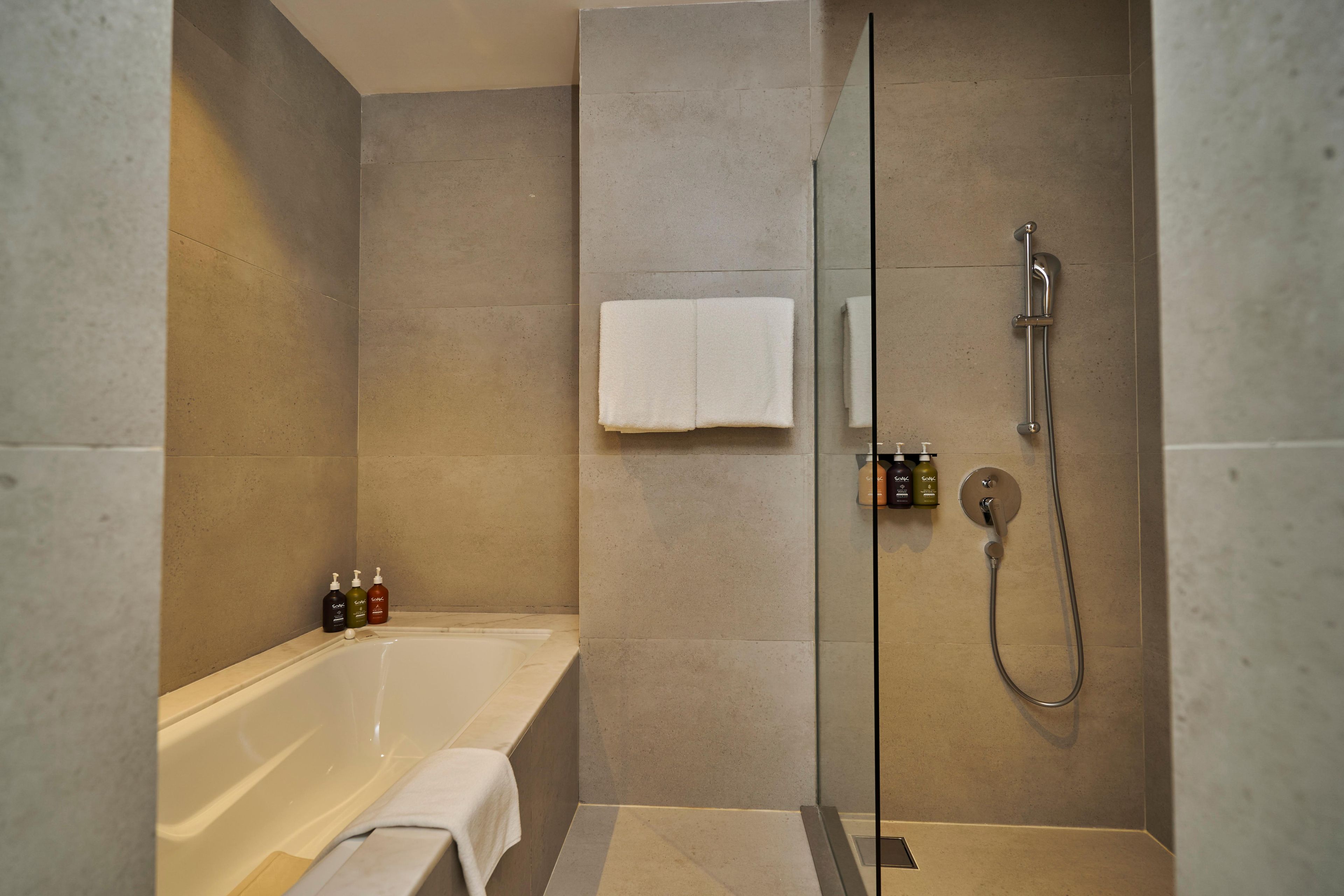 A modern bathroom with a bathtub, a glass-enclosed shower, and a towel rack.