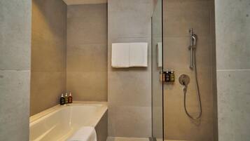 A modern bathroom with a bathtub, a glass-enclosed shower, and a towel rack.