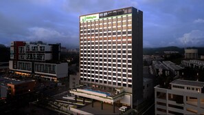 Een Holiday Inn hotel met een modern ontwerp, met een opvallend verticaal bord, meerdere verdiepingen en een zwembad op het dak.