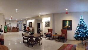 Spaziosa hall d'albergo con area ristorazione, albero di Natale e reception.