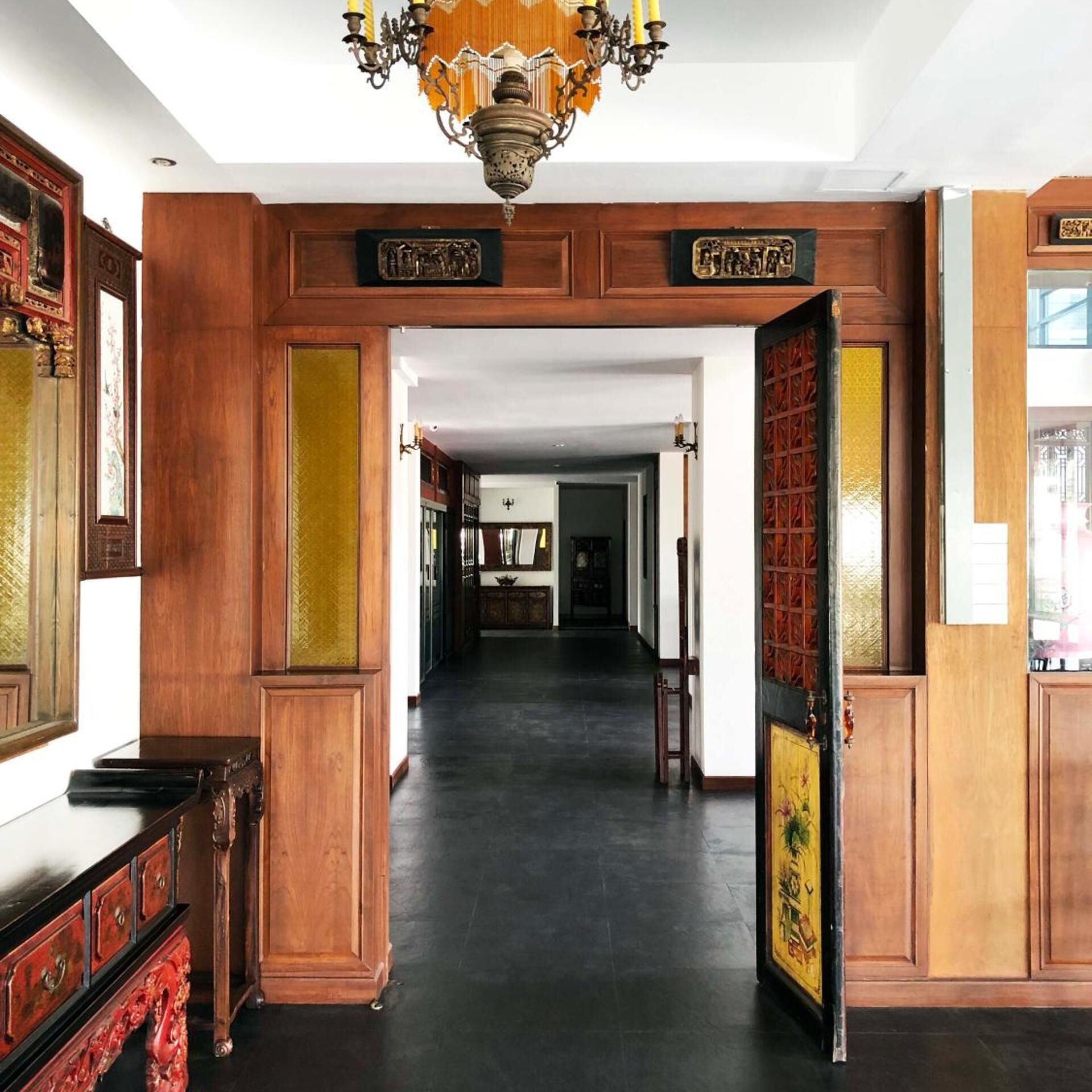 A hallway with wooden paneling, a chandelier, and a door with traditional Chinese characters.