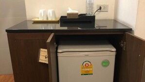 A compact kitchenette with a refrigerator, a small countertop, and a cabinet. - Hotel IYA (Khlong Luang)