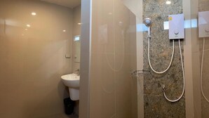 Une salle de bain moderne avec une douche à parois de verre, un lavabo blanc et un mur en marbre.