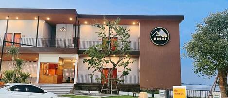 A modern hotel with a sign reading 'SINAI,' a car parked in front, and a charging station.