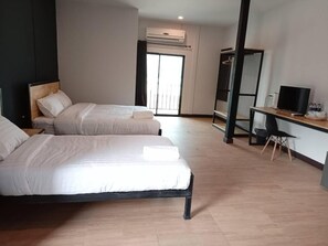 A hotel room with two beds, a desk, a TV, and an air conditioning unit. - Sinai Hotel (Nikhom Phatthana)