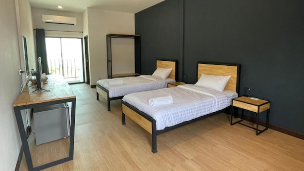 Une chambre d’hôtel avec deux lits, un bureau, une chaise, une petite table et un miroir.