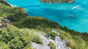A coastal landscape with multiple islands, clear turquoise waters, and a boat in the distance. - Suhotel Suratthani (Surat Thani)