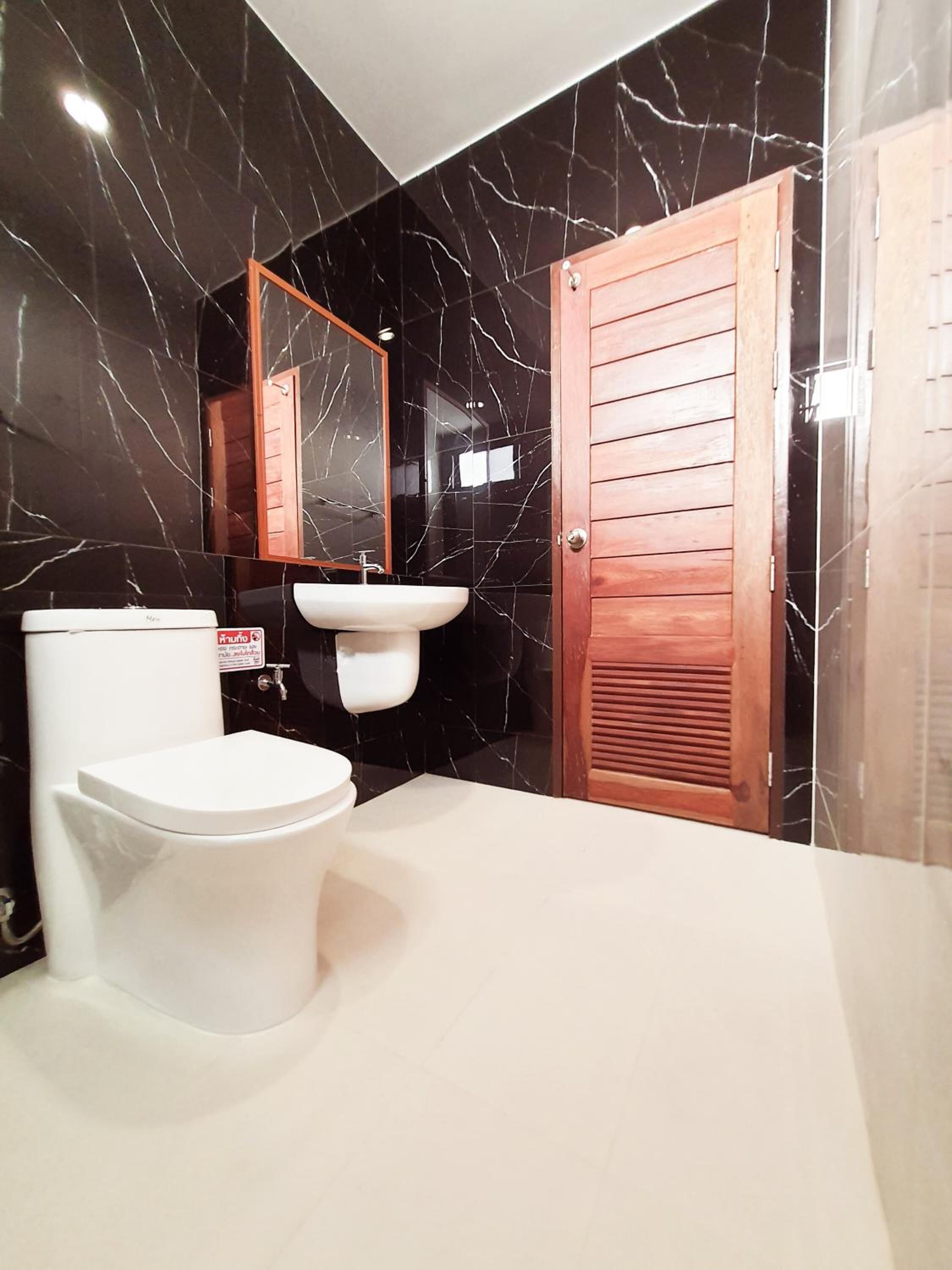 A bathroom with a white toilet, a sink, and a mirror.
