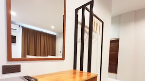 A hotel room with a wooden desk, a chair, a large mirror, and a staircase. - Suhotel Suratthani (Surat Thani)