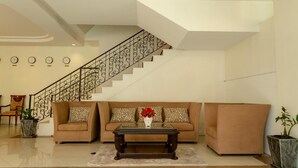 A modern living room with a staircase, a sofa set, a coffee table, and decorative elements. - Ivory Palace Hotel (Pattaya)