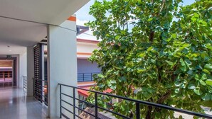 Un espacio interior moderno con barandilla metálica, un árbol y vistas a edificios.