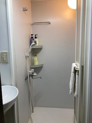 A small, modern bathroom with a toilet, sink, shower, and towel rack. - Greenhotel (Tokyo)
