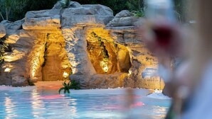 A pool area with rock formations and lighting. - Avaton Luxury Resort and Spa (Volvi)