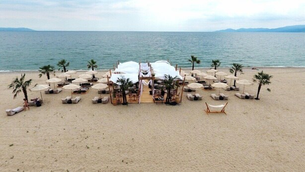 A beach wedding setup with a tent, lounge chairs, and umbrellas. - Avaton Luxury Resort and Spa (Volvi)