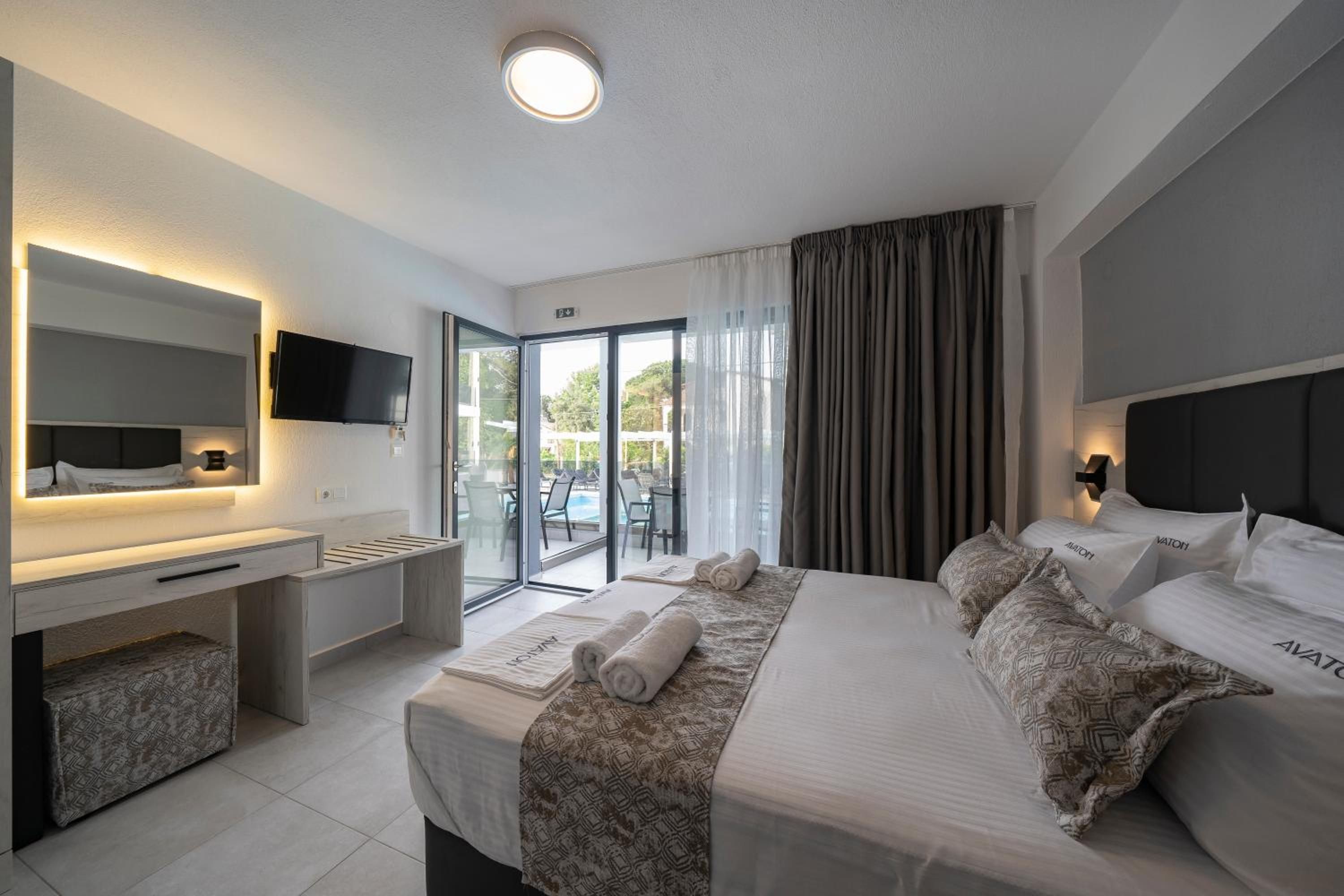 Habitación de hotel con cama, escritorio, televisor y vistas al exterior.
